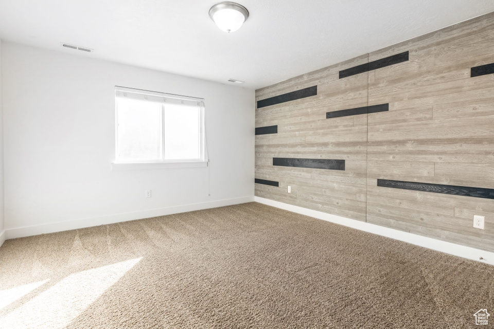 Carpeted spare room featuring wooden walls