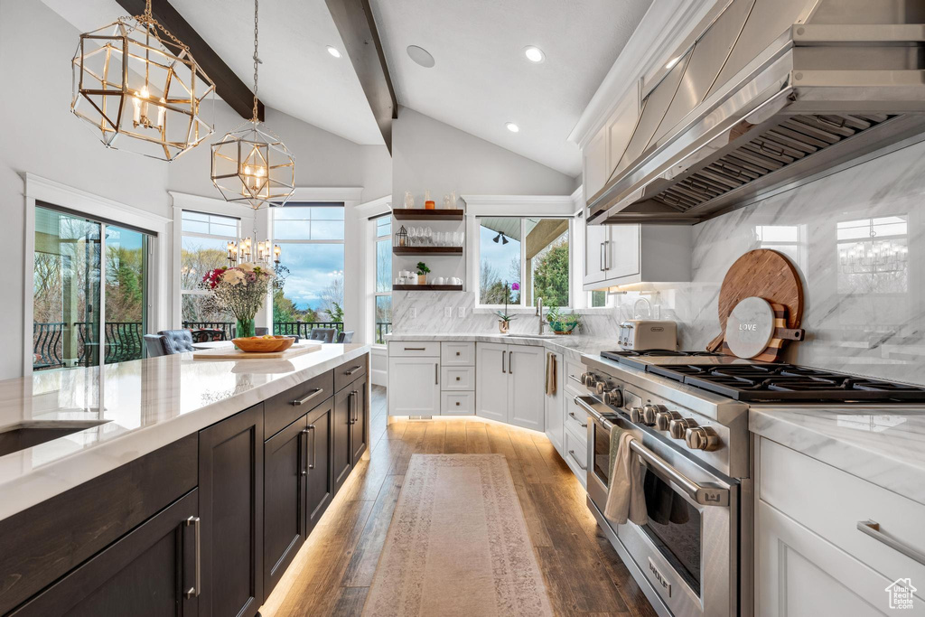 Kitchen featuring white cabinetry, double oven range, wall chimney exhaust hood, and backsplash