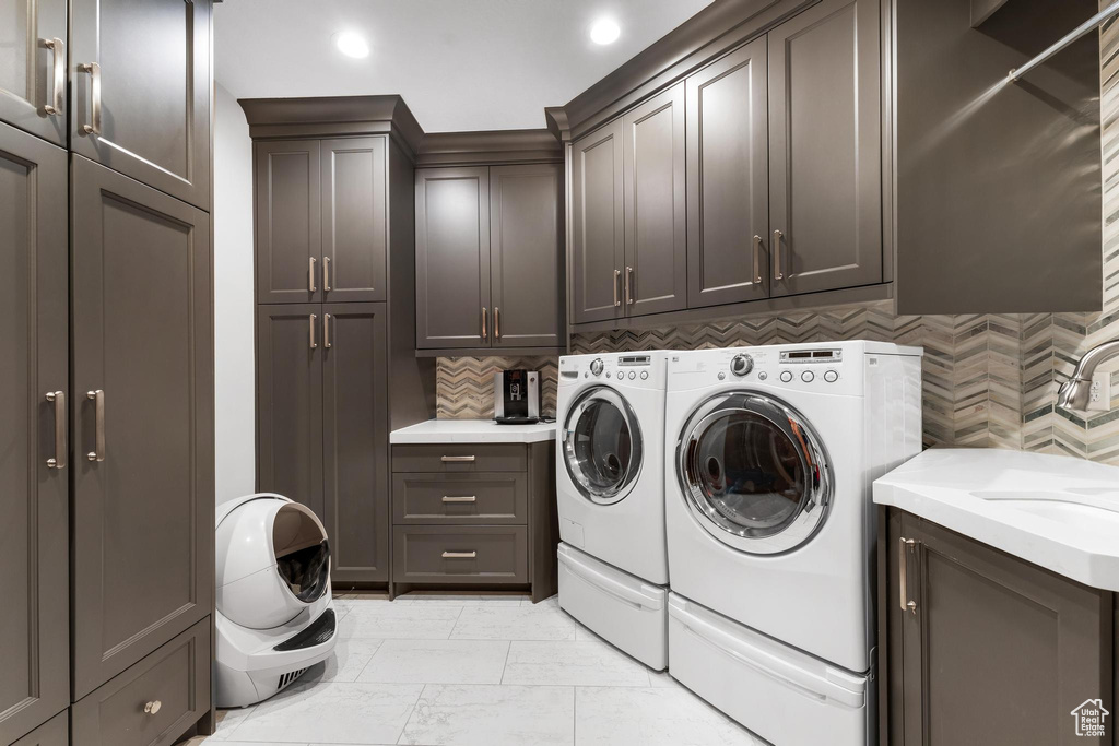 Laundry area featuring cabinets, washing machine and dryer, and light tile floors