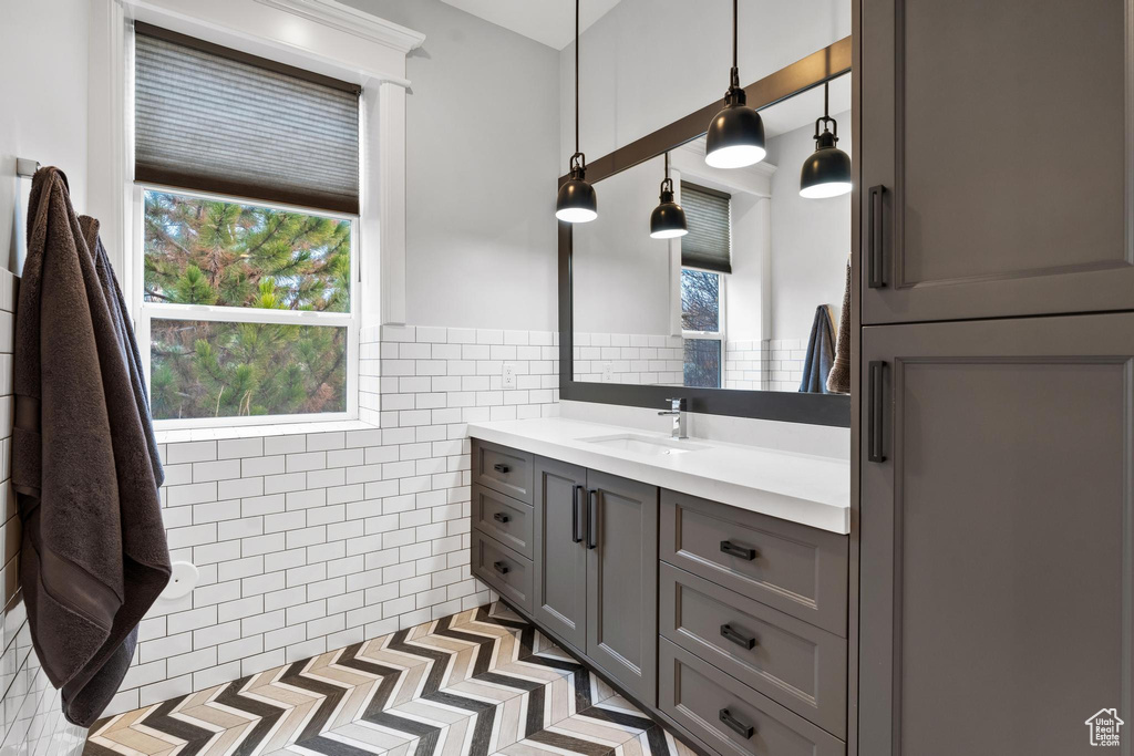 Bathroom featuring tasteful backsplash, large vanity, tile walls, and tile flooring
