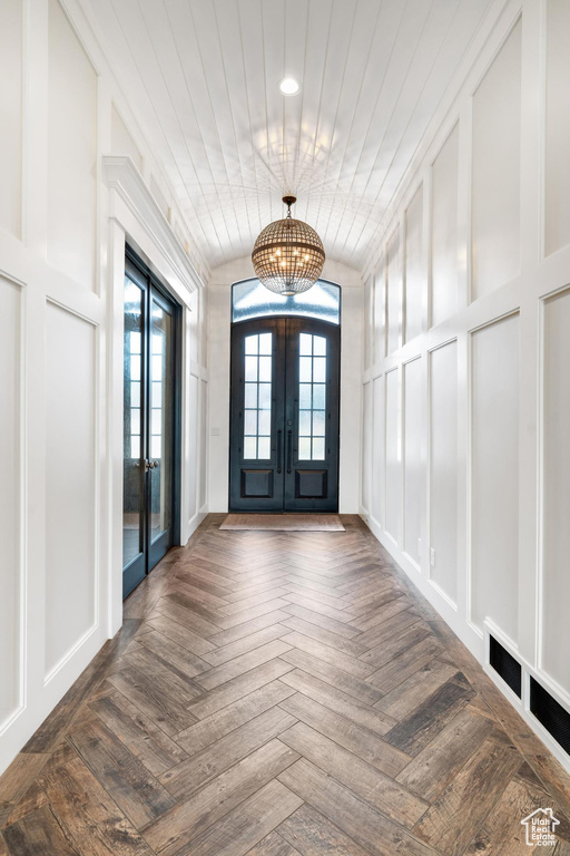 Entrance foyer with dark parquet flooring, wooden ceiling, and french doors