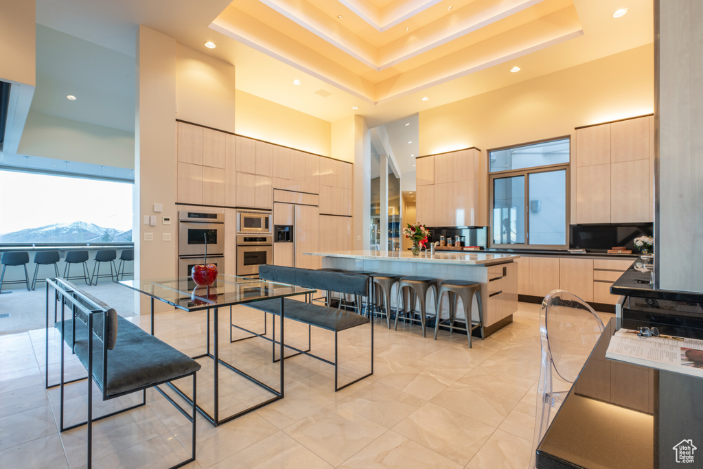 Interior space with light tile flooring, light brown cabinets, a center island, and a breakfast bar area