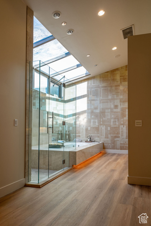 Bathroom featuring a skylight, wood-type flooring, and shower with separate bathtub