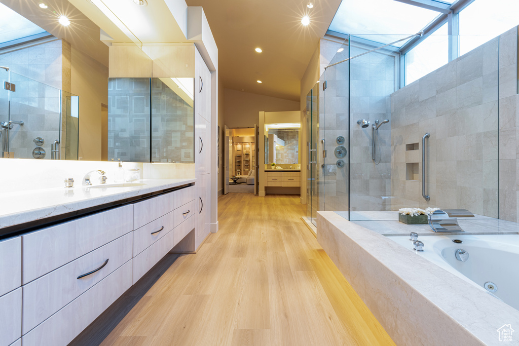 Bathroom with large vanity, a towering ceiling, independent shower and bath, and wood-type flooring