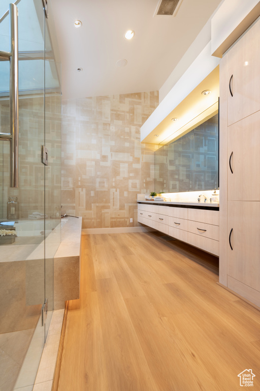 Bathroom featuring a shower with shower door, hardwood / wood-style flooring, tile walls, and vanity