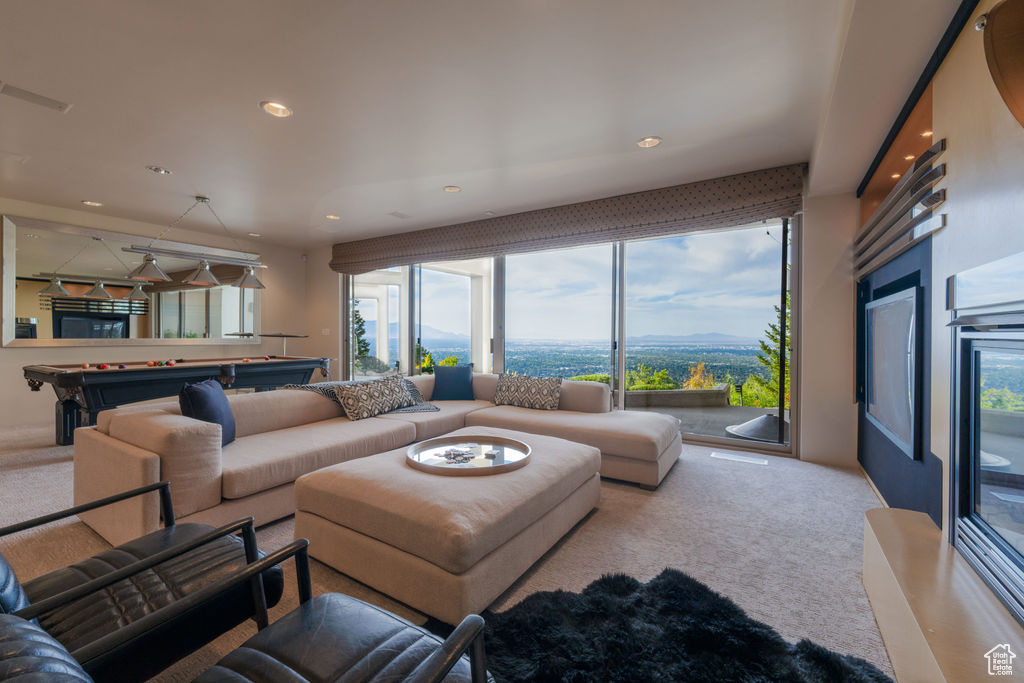 Living room featuring light colored carpet, billiards, and a wealth of natural light