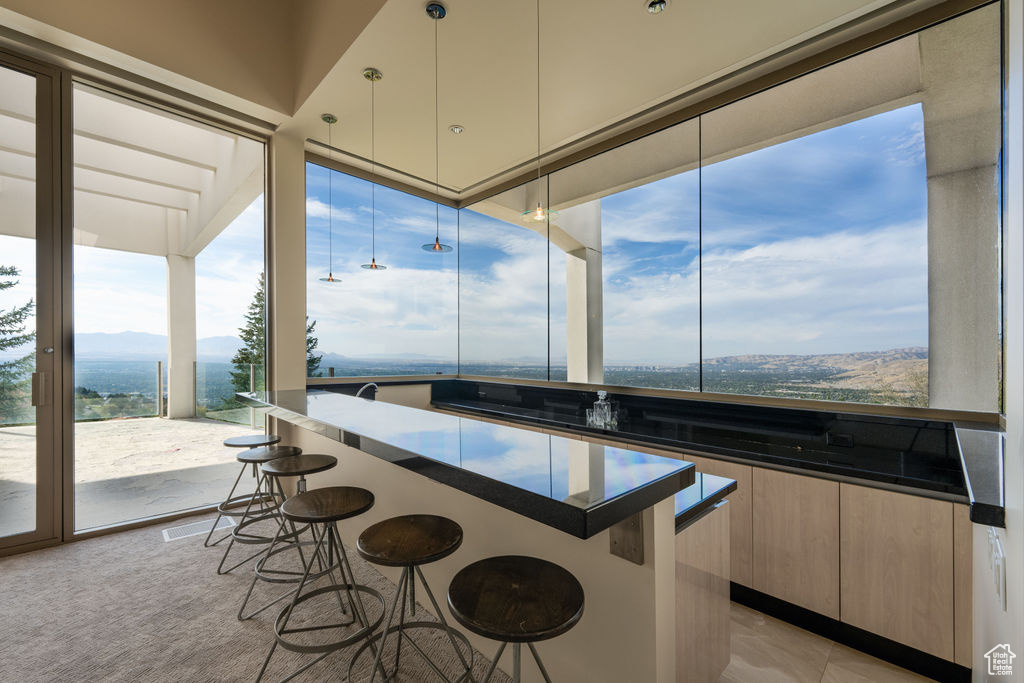 Kitchen with a mountain view, a breakfast bar area, light colored carpet, and a center island