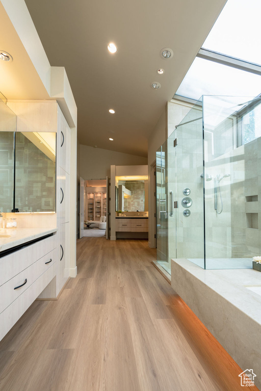 Bathroom featuring walk in shower, vaulted ceiling, wood-type flooring, and vanity