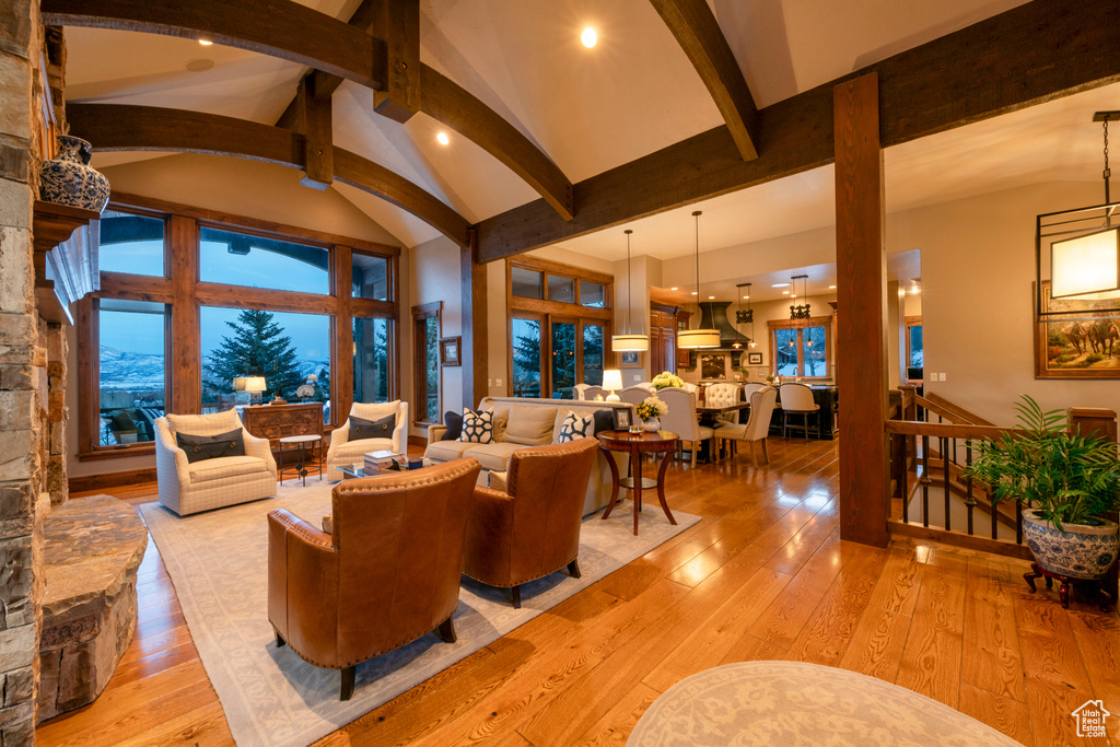 Living room with a chandelier, light hardwood / wood-style flooring, beamed ceiling, and high vaulted ceiling