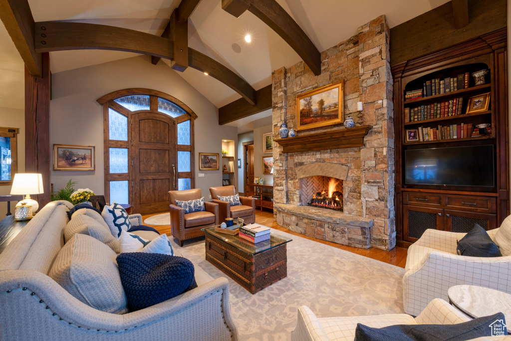 Living room featuring light wood-type flooring, beam ceiling, a fireplace, and high vaulted ceiling