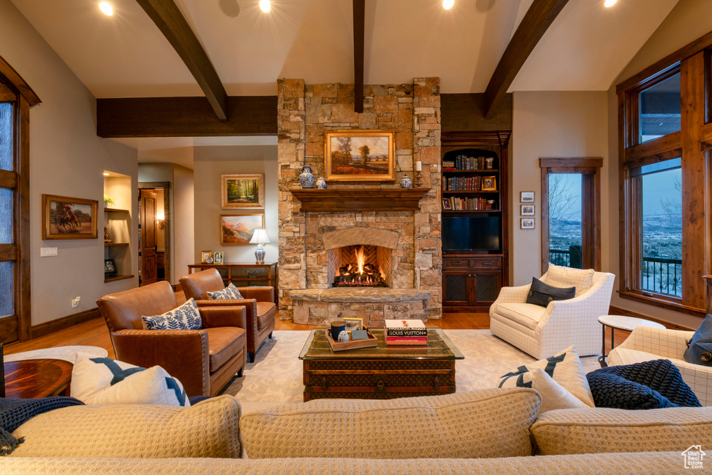 Living room with light hardwood / wood-style flooring, lofted ceiling with beams, a fireplace, and built in features