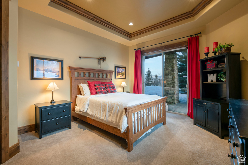 Carpeted bedroom featuring access to outside, a raised ceiling, and ornamental molding