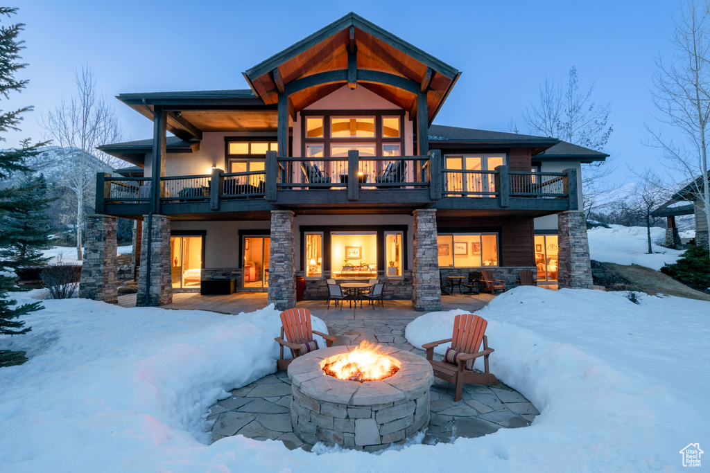 Snow covered property featuring a balcony, a patio area, and a fire pit
