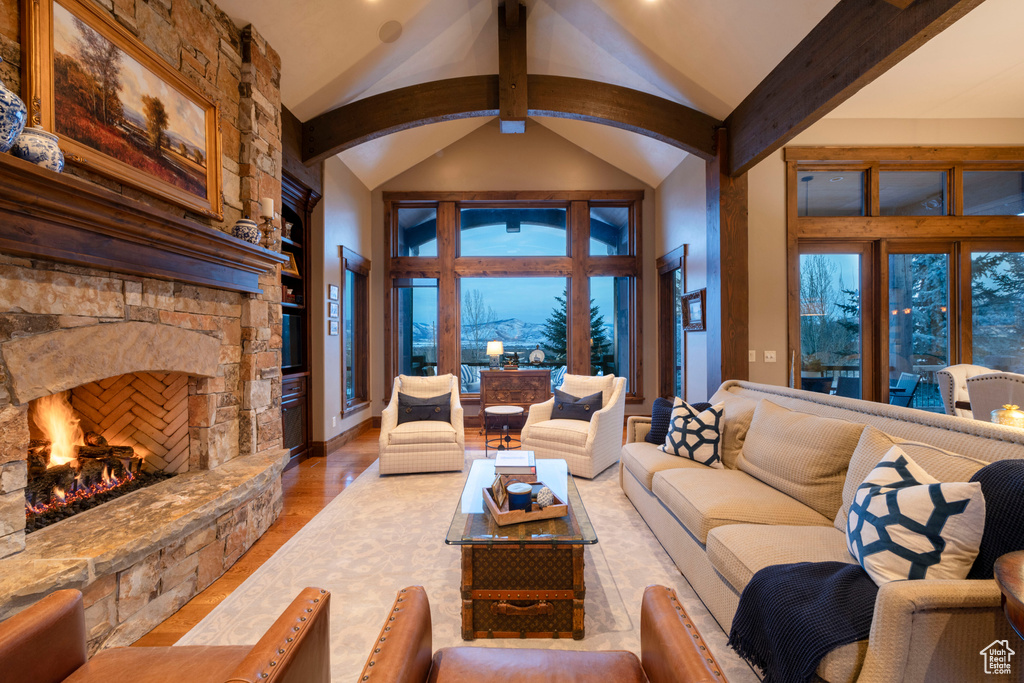 Living room featuring light hardwood / wood-style floors, beam ceiling, a fireplace, and high vaulted ceiling