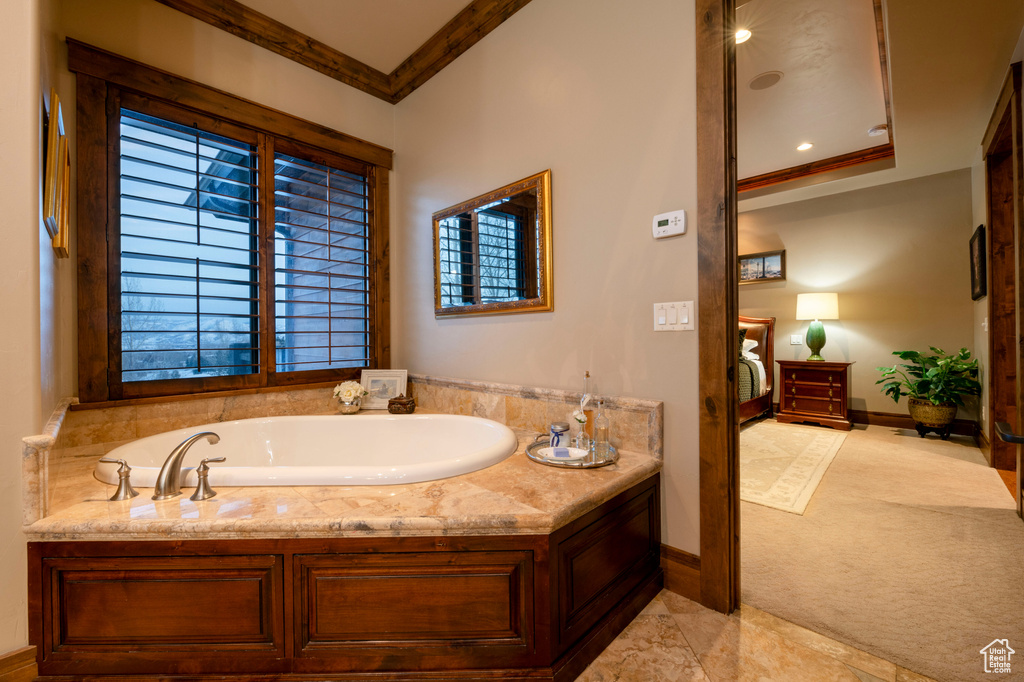 Bathroom featuring a raised ceiling, tile floors, crown molding, and a bath