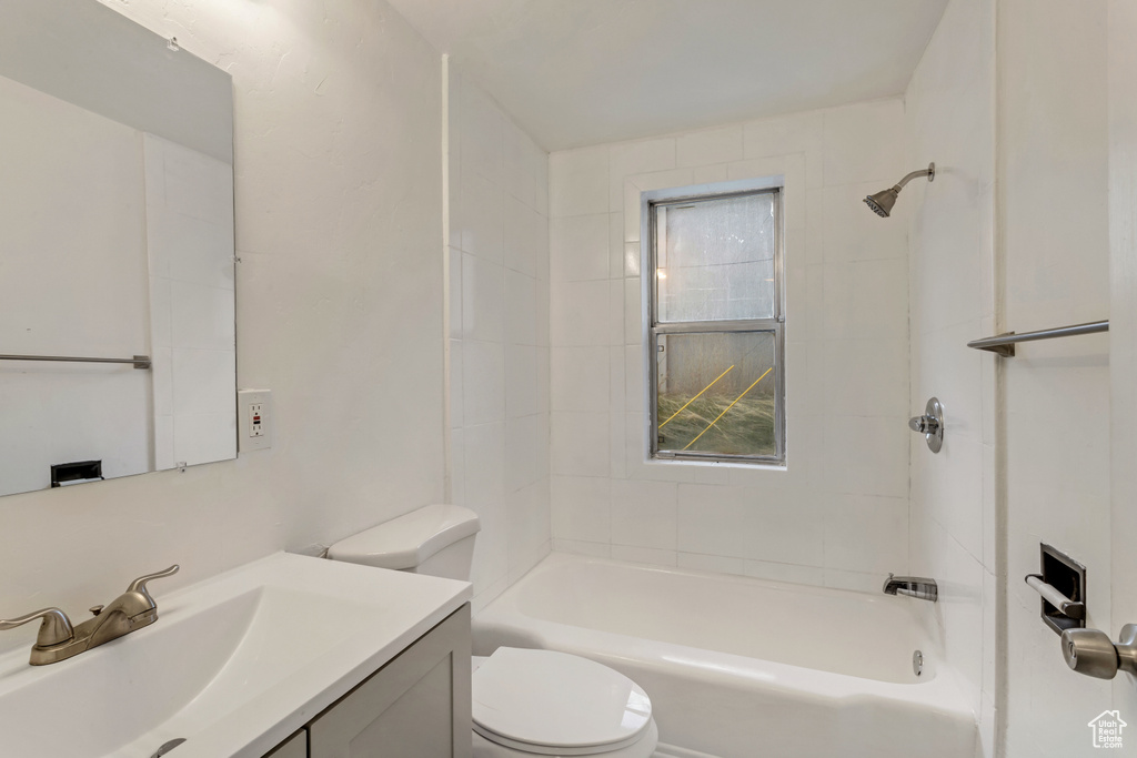 Full bathroom featuring large vanity, tiled shower / bath, and toilet