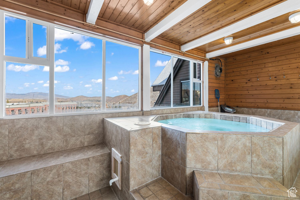 Interior space with wood ceiling, beamed ceiling, a hot tub, and a mountain view