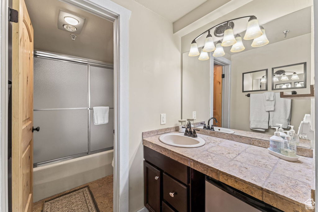 Bathroom with vanity, bath / shower combo with glass door, and tile flooring