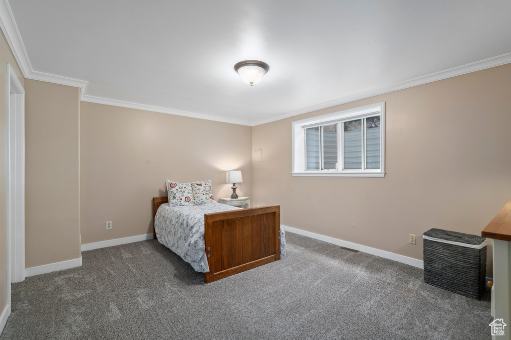 Bedroom with ornamental molding and dark carpet