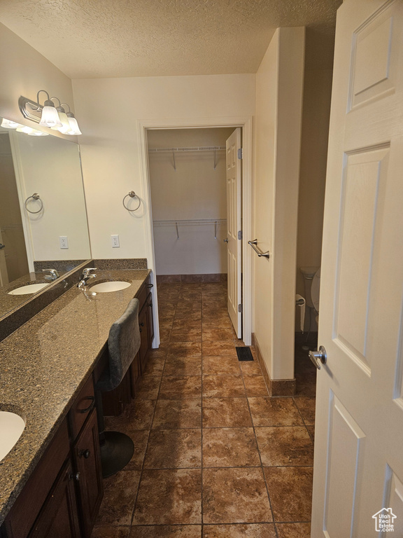 Bathroom with vanity, tile flooring, and a textured ceiling