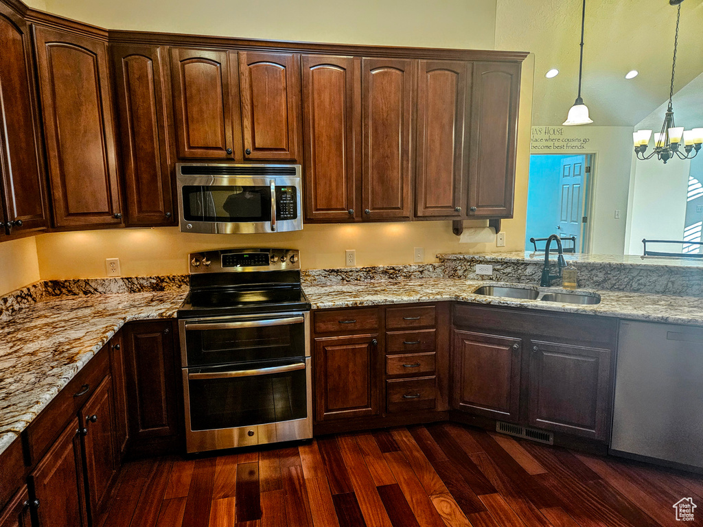 Kitchen featuring dark hardwood / wood-style flooring, stainless steel appliances, a chandelier, sink, and decorative light fixtures