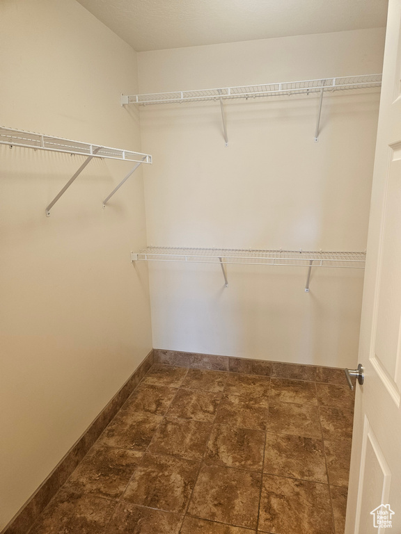 Spacious closet featuring dark tile flooring