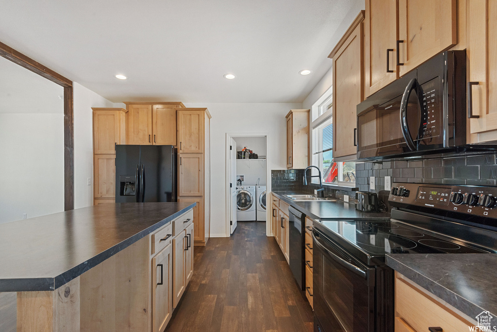 Kitchen featuring black appliances, a center island, dark hardwood / wood-style floors, sink, and washing machine and clothes dryer
