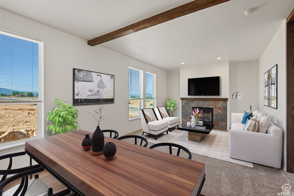 Interior space featuring a wealth of natural light, beamed ceiling, light carpet, and a tile fireplace