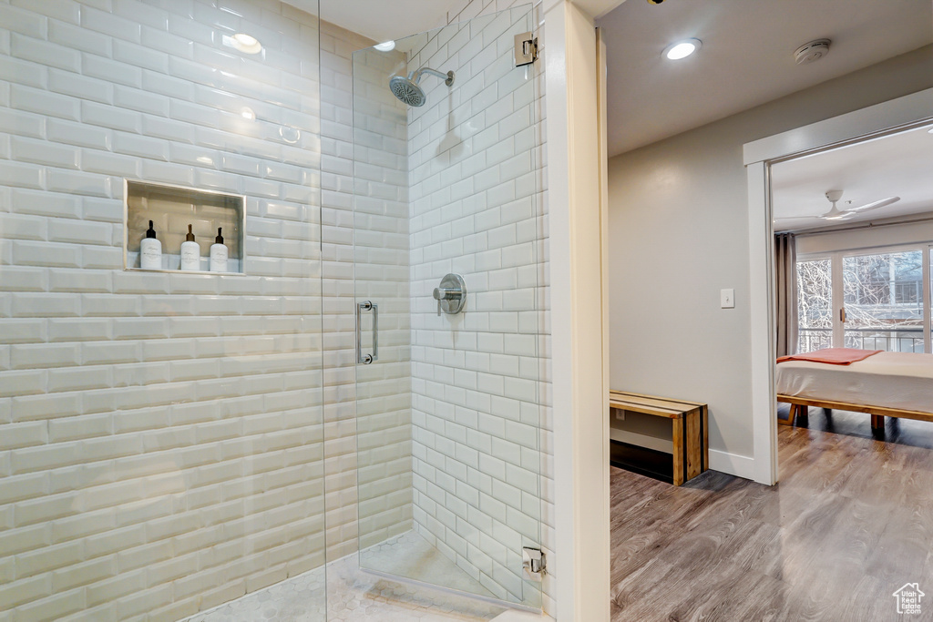 Bathroom featuring hardwood / wood-style floors, ceiling fan, and walk in shower