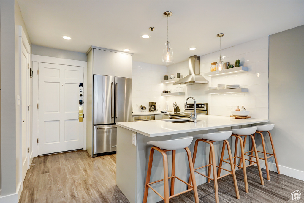 Kitchen with tasteful backsplash, light wood-type flooring, fume extractor, and stainless steel fridge