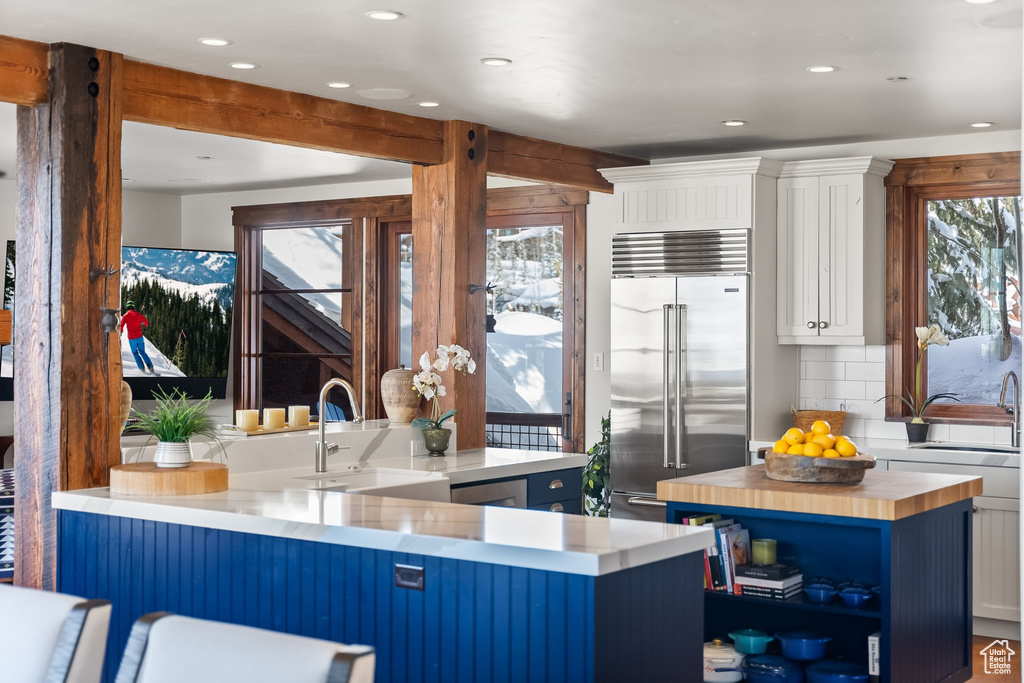 Kitchen featuring kitchen peninsula, built in fridge, sink, and white cabinetry