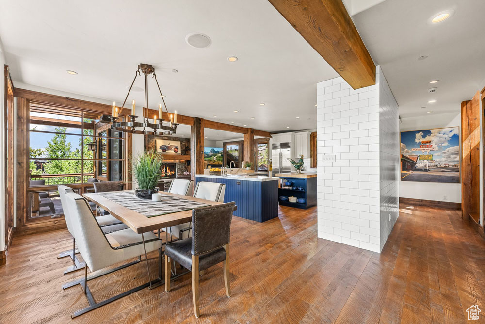 Dining space featuring beamed ceiling, sink, hardwood / wood-style flooring, and brick wall