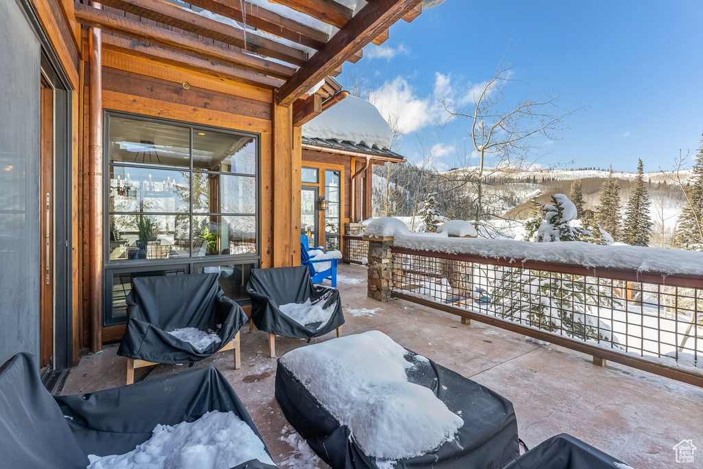 Snow covered patio featuring a balcony
