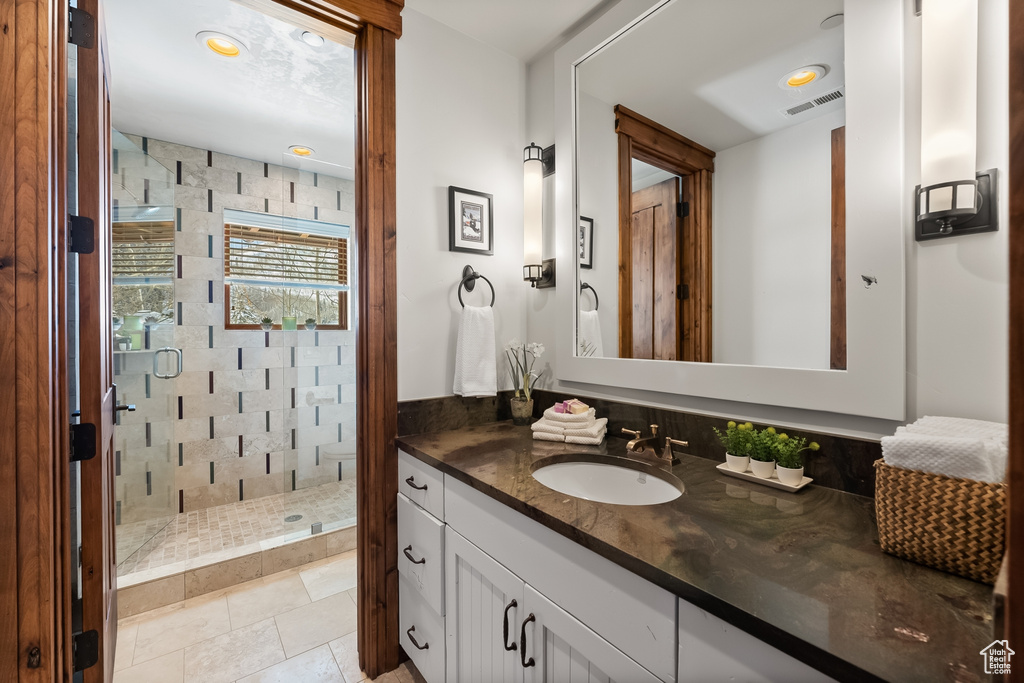 Bathroom with tile flooring, a tile shower, and oversized vanity