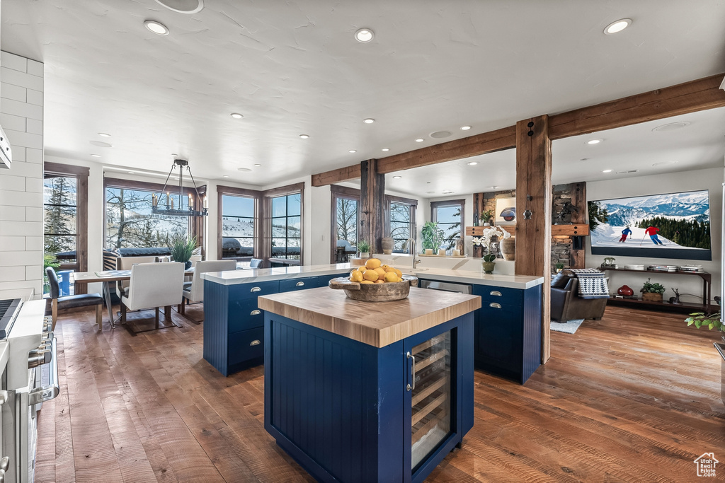 Kitchen with a healthy amount of sunlight, a center island, wine cooler, and dark hardwood / wood-style floors