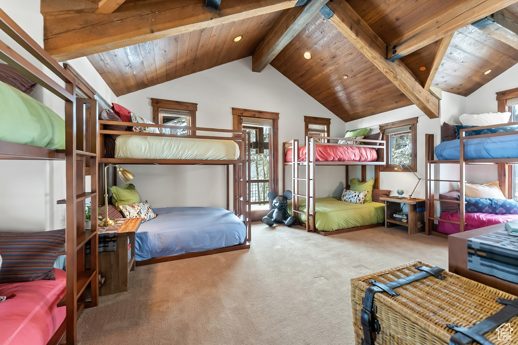 Carpeted bedroom with multiple windows, vaulted ceiling with beams, and wooden ceiling