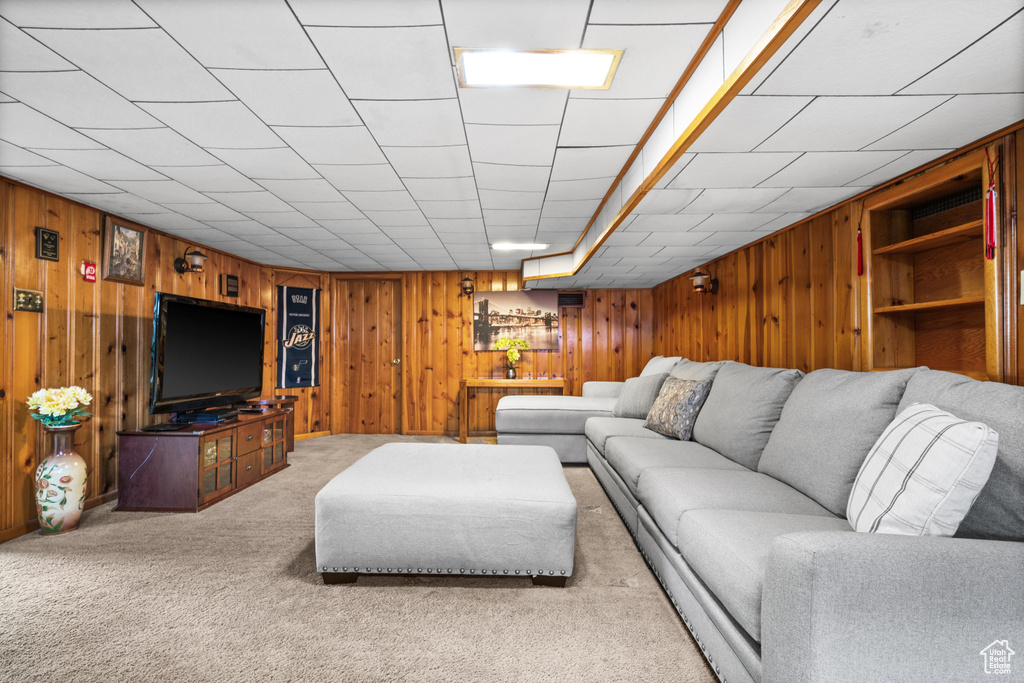 Carpeted living room featuring wooden walls