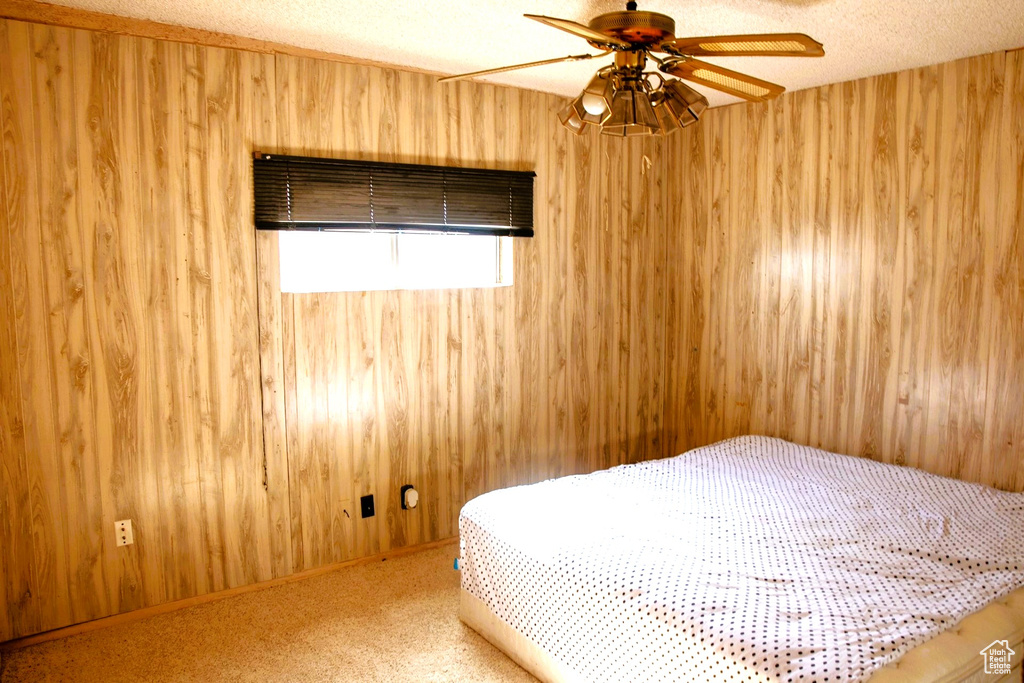 Unfurnished bedroom with carpet floors, ceiling fan, a textured ceiling, and wood walls