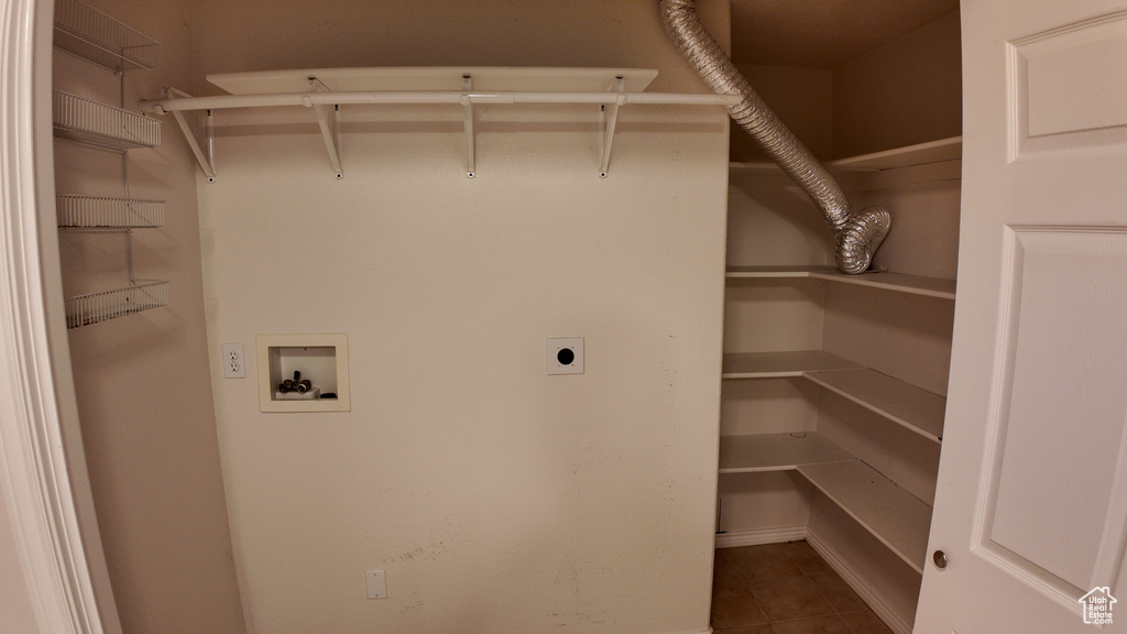 Laundry area with hookup for an electric dryer, dark tile flooring, and washer hookup