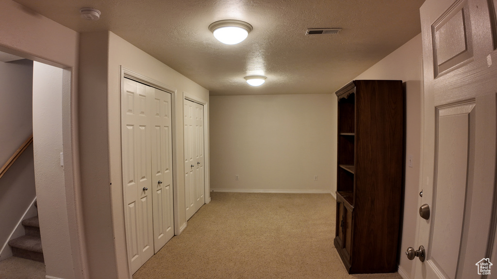 Hall with light carpet and a textured ceiling