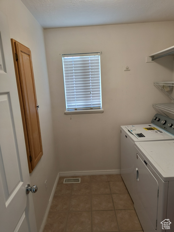 Laundry area with light tile flooring and washer and clothes dryer