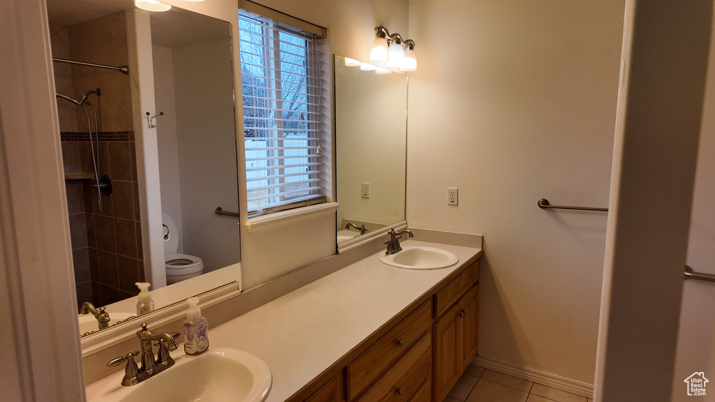 Bathroom featuring dual bowl vanity, tile flooring, and toilet