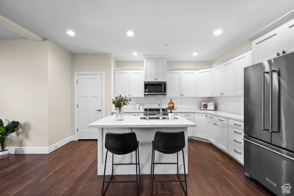 Kitchen with dark wood-type flooring, stainless steel appliances, and white cabinets