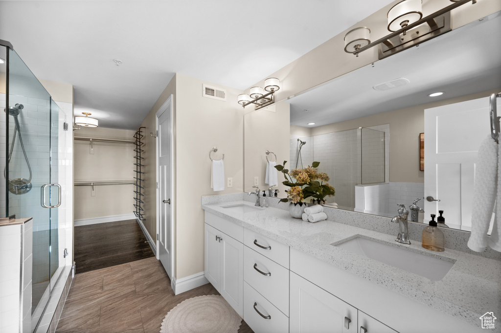 Bathroom featuring dual vanity, walk in shower, and tile flooring