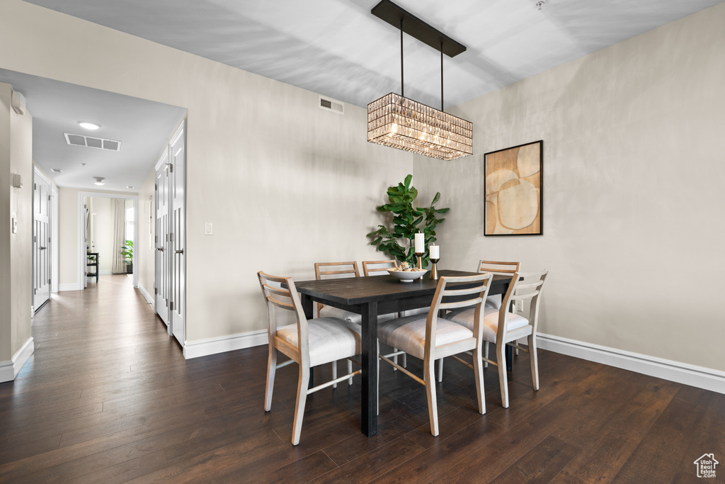 Dining space with dark hardwood / wood-style floors and a chandelier