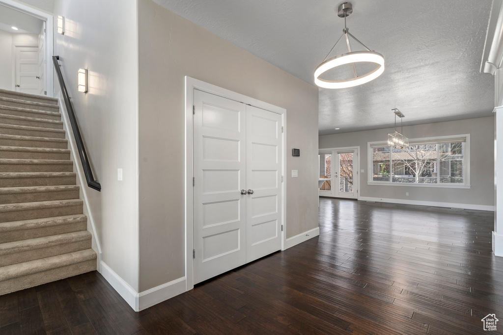 Entrance foyer with an inviting chandelier, dark wood-type flooring, and a textured ceiling