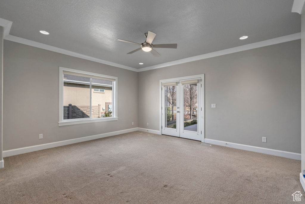 Spare room with ornamental molding, light colored carpet, ceiling fan, and french doors