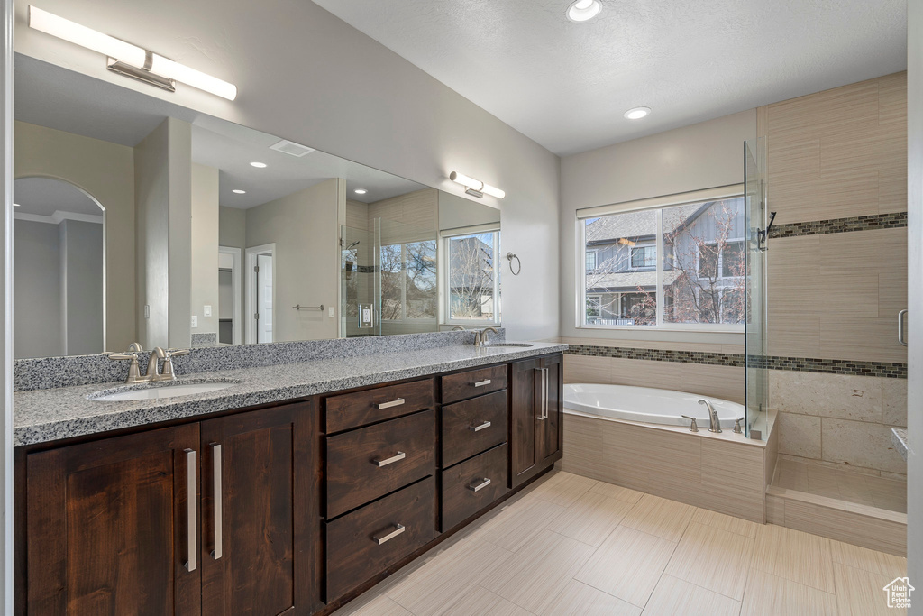 Bathroom with large vanity, separate shower and tub, tile floors, and double sink