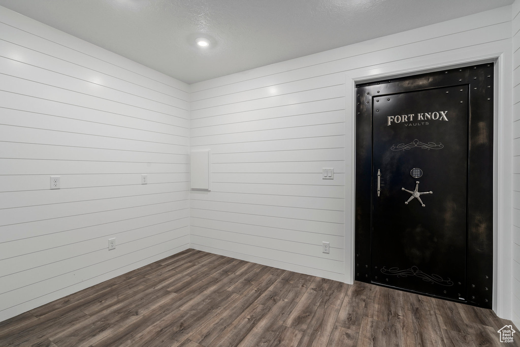 Unfurnished room with wood walls and dark hardwood / wood-style floors