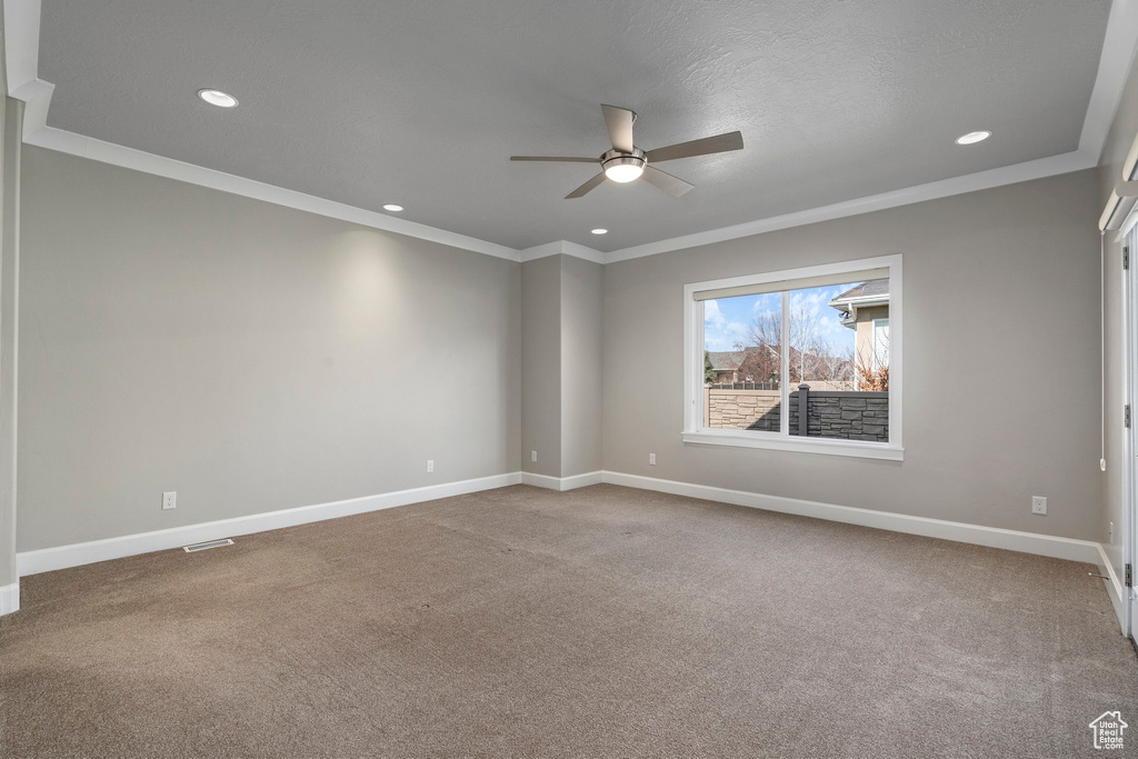 Empty room featuring light carpet, crown molding, and ceiling fan
